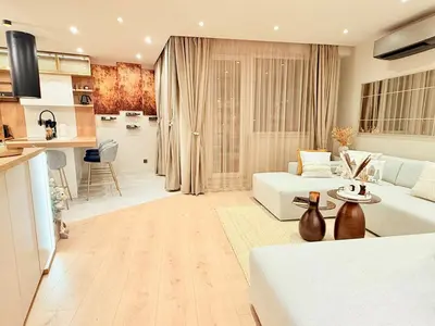 a living room with a white couch and a kitchen at Lux Boutique 2 BDR apartment right next ski gondola lift in Bansko