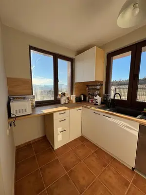 a kitchen with white cabinets and large windows at Къща за гости Пегас in Velingrad