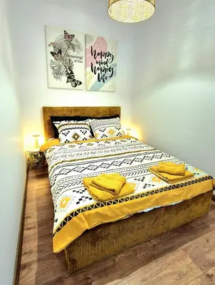 a bedroom with a bed with yellow pillows on it at Kapana Garden - 4 persons luxury apartment in Plovdiv