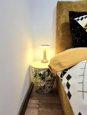 a table with a lamp on it next to a bed at Kapana Garden - 4 persons luxury apartment in Plovdiv