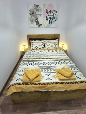a bedroom with a large bed with two yellow pillows at Kapana Garden - 4 persons luxury apartment in Plovdiv