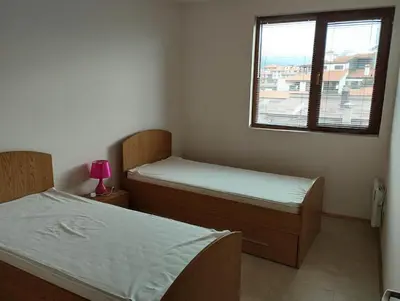 two beds in a small room with a window at Bansko View 3 in Bansko