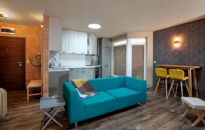 a living room with a blue couch and a kitchen at Plovdiv ArtNest - 1-Bedroom Cozy Apartments in Plovdiv