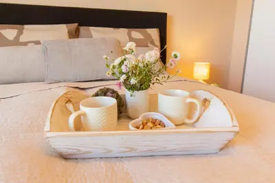 a tray with cups and cookies on a bed at Domus Apartments Vista in Plovdiv