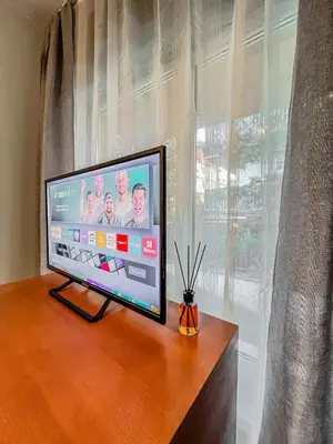 a flat screen tv sitting on a table next to a window at Fireplace Apartment near Bus & Train Station in Bansko