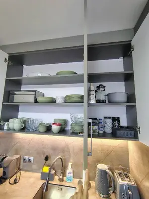 a kitchen with a sink and a shelf with dishes at Family Apartment Royal Tower in Bansko