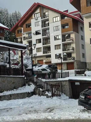 a snow covered parking lot in front of a building at Lucky SP apartments -Pamporovo in Bŭnzareto