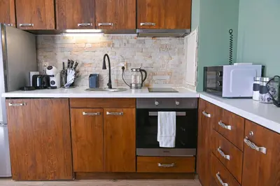 a kitchen with wooden cabinets and a stove top oven at Comfortable 2-Bedroom Apartment Near the Ski Lift by Flat Mаnаger in Bansko