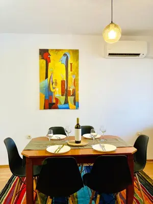 a dining room table with chairs and a painting at Spacious & Classy 2BDR Apartment with 2 Baths in Plovdiv Centre in Plovdiv