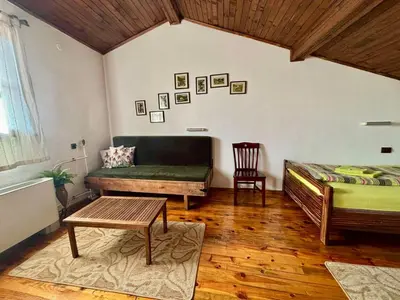 a room with a bed and a bench and a table at Семеен хотел-ресторант Маламовата къща in Gotse Delchev