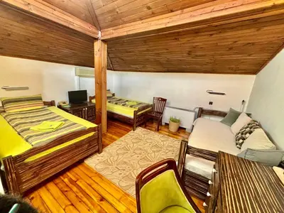 a room with two beds and a desk and a tv at Семеен хотел-ресторант Маламовата къща in Gotse Delchev