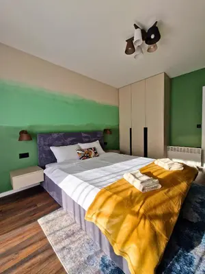 a bedroom with a large bed with a green wall at By The Pool Apartments #7 in Velingrad