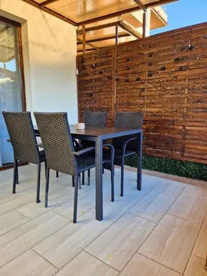 a dining room table with chairs and a wooden wall at By The Pool Apartments #7 in Velingrad