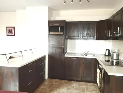 a kitchen with dark wood cabinets and white counter tops at Dreaming apartment with tree Mountain view in Borovets