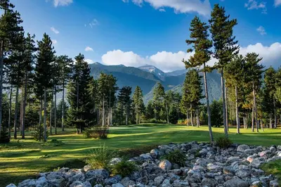 a golf course with rocks and trees and mountains at Studio 4, 4min walk to slope at Predela2 Bansko in Bansko