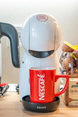 a coffee maker is pouring coffee into a red cup at The Urban Pulse Stylish Flat in Sofia