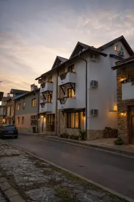 a building on a street with a car parked in front at Хотел Ривърсайд Анекс in Bansko