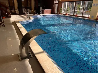 a large swimming pool with blue water in a building at Princeps De Cura Bansko in Bansko