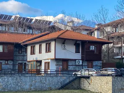 a white house with a red roof and some buildings at Private Studio 500m from Gondola in Bansko