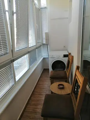 a living room with windows and a table and a stove at Апартамент Light blue in Troyan