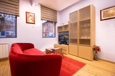a living room with a red chair and a cabinet at Central 2BR Near Vitosha - Calm, Spacious Stay in Sofia