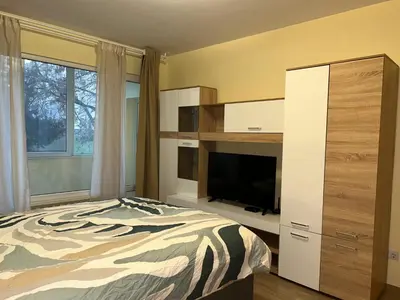 a bedroom with a bed and a tv and a dresser at Flat in Darvenitsa near Church St George the Victorious in Sofia