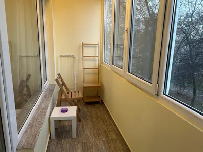 a room with a chair and a table and windows at Flat in Darvenitsa near Church St George the Victorious in Sofia