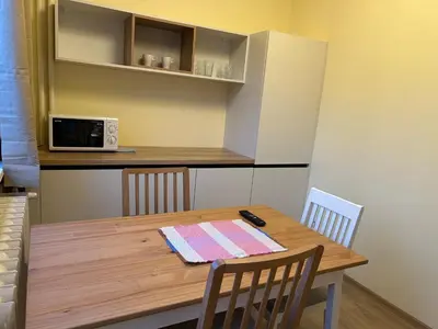 a kitchen with a wooden table with chairs and a microwave at Flat in Darvenitsa near Church St George the Victorious in Sofia