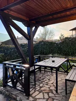 a picnic table and bench under a wooden roof at RhodoNest in Kara Agach