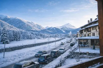 a snow covered street with cars parked on the road at Ametist - Comfort by the Gondola Lift in Bansko