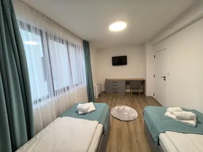 two beds in a room with a window and a desk at Карина - къща за гости in Ognyanovo