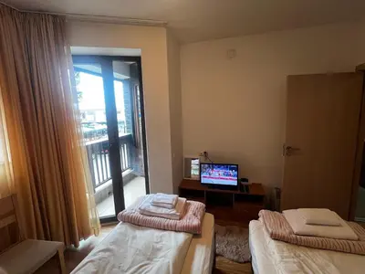a room with two beds and a television and a balcony at Lucky Star Bansko Next to the Ski Lift with FREE Parking in Bansko