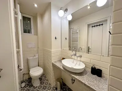 a bathroom with a sink and a toilet and a mirror at Elegant 2BDR Apt for groups and family - Fast Wi-Fi in Sofia