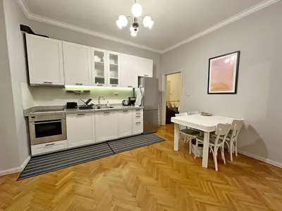 a kitchen with white cabinets and a table and a dining room at Elegant 2BDR Apt for groups and family - Fast Wi-Fi in Sofia
