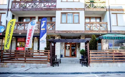 a building with flags in front of it at Pirin SkiLift Apartment - Cozy & Modern App in Bansko, 100 m to the Gondola in Bansko