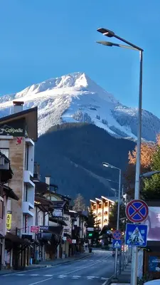 a city street with a snow covered mountain in the background at Pirin SkiLift Apartment - Cozy & Modern App in Bansko, 100 m to the Gondola in Bansko