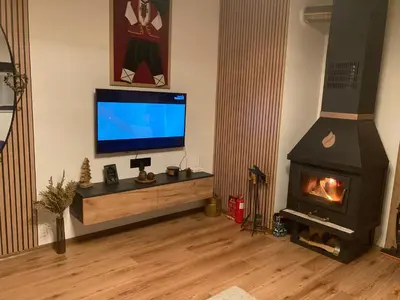 a living room with a fireplace and a flat screen tv at Студио за гости Петрови in Bansko