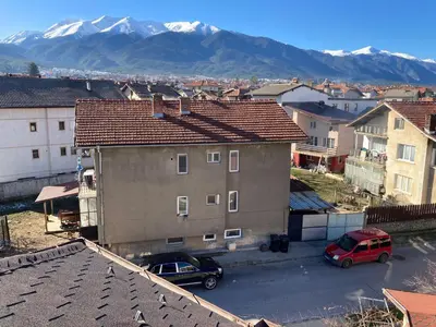 a city with cars parked in a parking lot with mountains at Студио за гости Петрови in Bansko