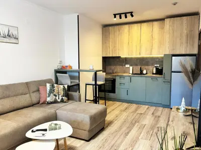 a living room with a couch and a kitchen at Alpine Glow - Panoramic View near Gondola in Bansko
