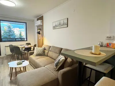 a living room with a couch and a table at Alpine Glow - Panoramic View near Gondola in Bansko