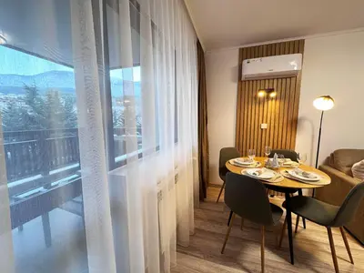 a dining room with a table and a large window at Alpine Glow - Panoramic View near Gondola in Bansko