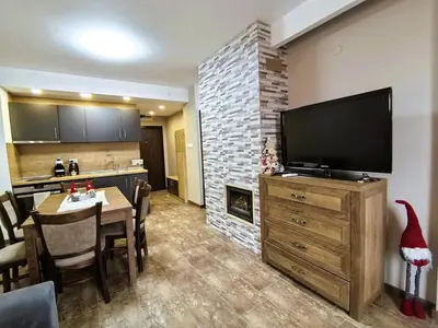 a living room with a large television and a table with chairs at Cozy 1BR Mountain View Suite for 4 Guests in Bansko