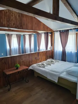 a bedroom with a bed and a table and windows at Old House - Стара Къща in Koprivshtitsa
