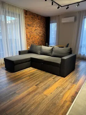 a black couch in a living room with wood floors at MedHill Stay - Medical University Area in Plovdiv