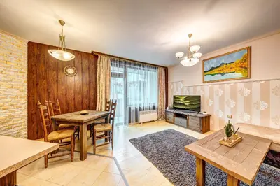 a living room with a table and a dining room at Апартамент Orpheus Forest in Pamporovo