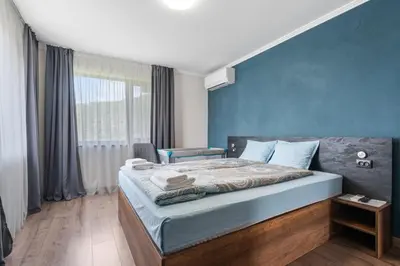 a bedroom with a bed with a blue wall at Къща за гости Мартинели