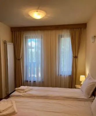 a bedroom with two beds and two windows at Апартаменти за гости Алекс in Pamporovo