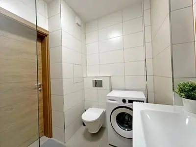 a bathroom with a toilet and a washing machine at Spacious bright cozy 2BDR fast Wi-Fi next to Park in Sofia