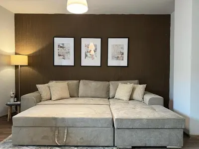 a couch in a living room with three pictures on the wall at Top Centre Plovdiv Apartment for 4 Guests & Parking in Plovdiv