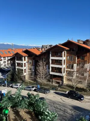 an apartment complex with cars parked in a parking lot at Smart Stay - Refurbished Studio with Balcony and Parking in Bansko